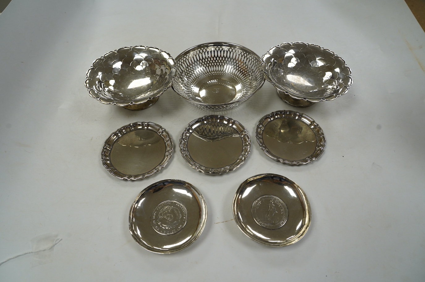 A pair of George V silver pedestal bonbon dishes, Birmingham, 1916, diameter 12.7cm, a set of four similar silver glass coasters, a silver bonbon bowl and a pair of Chinese white metal dishes with inset coin bases by Wan